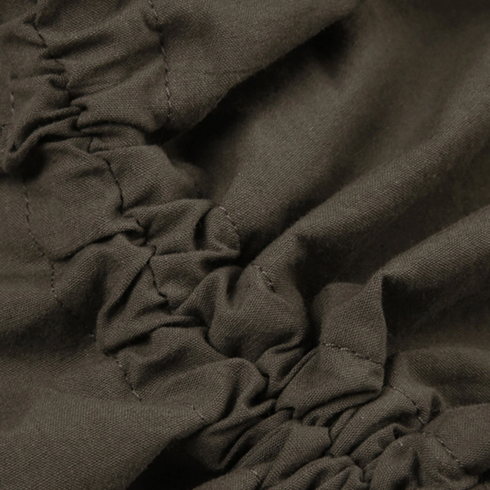 Close-up fabric texture detail of army green woven cotton with gathered ruched stitching and seam construction