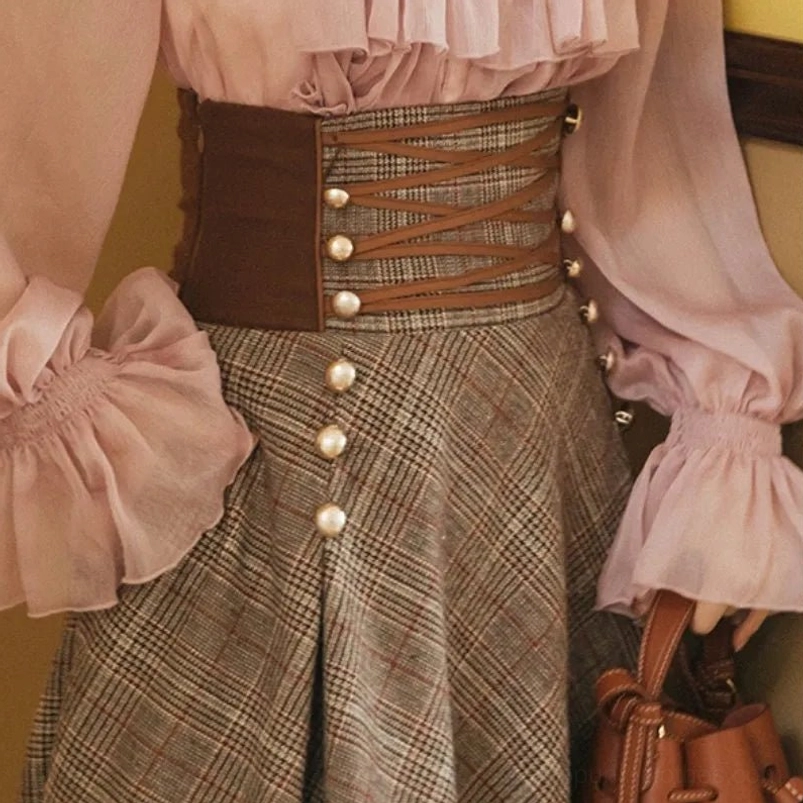 Close-up detail of leather corset waist panel with crisscross lace-up and pearl buttons on steampunk plaid skirt