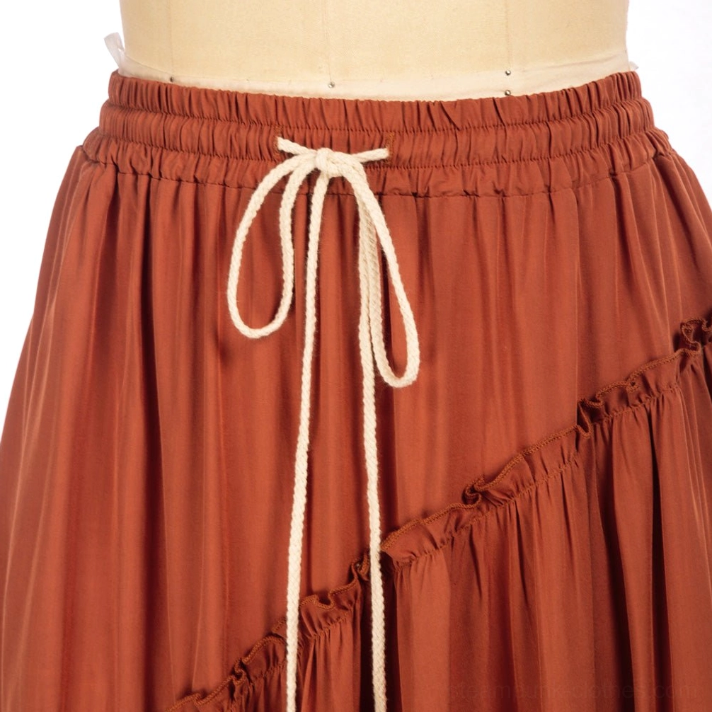 Close-up detail of maxi skirt elastic waistband with cotton drawstring, thick reinforced band, and ruffled edge trim showing quality construction