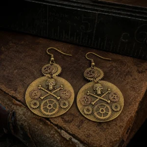 Bronze steampunk skull gear earrings with crossbone design on vintage leather desk with antique ruler, flat lay overhead view showcasing intricate mechanical details