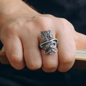 Steampunk skull ring worn on male hand middle finger overhead view with vintage book edge background