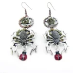 Paired steampunk spider drop earrings with bronze gears, silver spiders, and red spotted ladybug pendants on white background