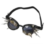 Black steampunk spike goggles with silver metal spikes and brass gear ornaments, front flat studio view showcasing dark tinted round lenses and industrial gothic aesthetic