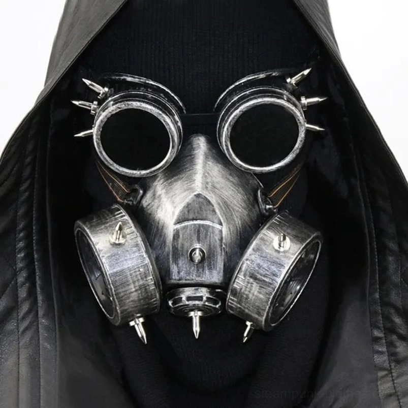 Steampunk spiked gas mask with welding goggles front view on model wearing black hooded leather coat - silver weathered metal finish with dual filter canisters and spike decorations
