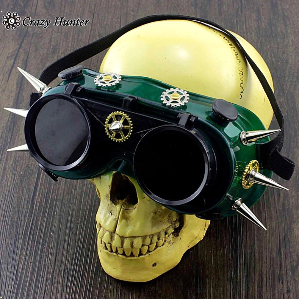 Steampunk spiked goggles front straight view with green frame, silver gears and spikes, black elastic adjustment strap on yellow skull mannequin head