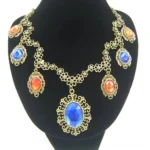 Steampunk statement necklace front view on mannequin featuring antiqued bronze filigree setting with large blue oval pendant and mixed orange-red faceted gemstones