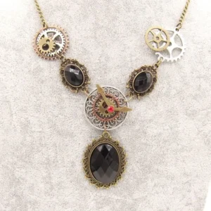 Steampunk vintage statement necklace overhead view featuring mixed metal gears, black faceted faux gemstones, and ornate filigree bezels on textured gray background