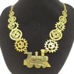 Gold-tone steampunk steam train necklace with gear chain links displayed on black velvet jewelry mannequin, showcasing intricate locomotive pendant detail and industrial chain design
