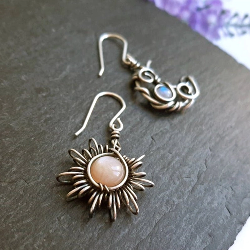 Celestial steampunk sun and moon earrings photographed on dark slate background with purple flower, bohemian style jewelry showcase