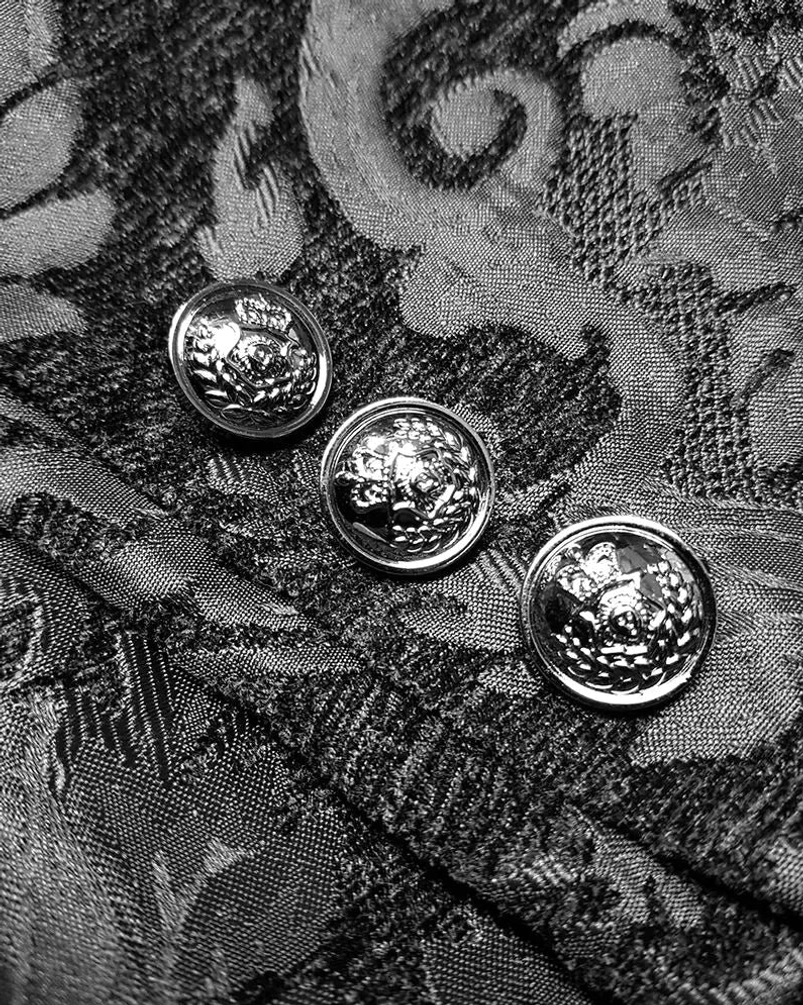 Embossed silver metal button detail on black damask steampunk tailcoat fabric close-up