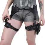 Black leather steampunk thigh holster bag front three-quarter view on tattooed model, showcasing metal buckle straps, utility pouch design, and industrial gothic aesthetic