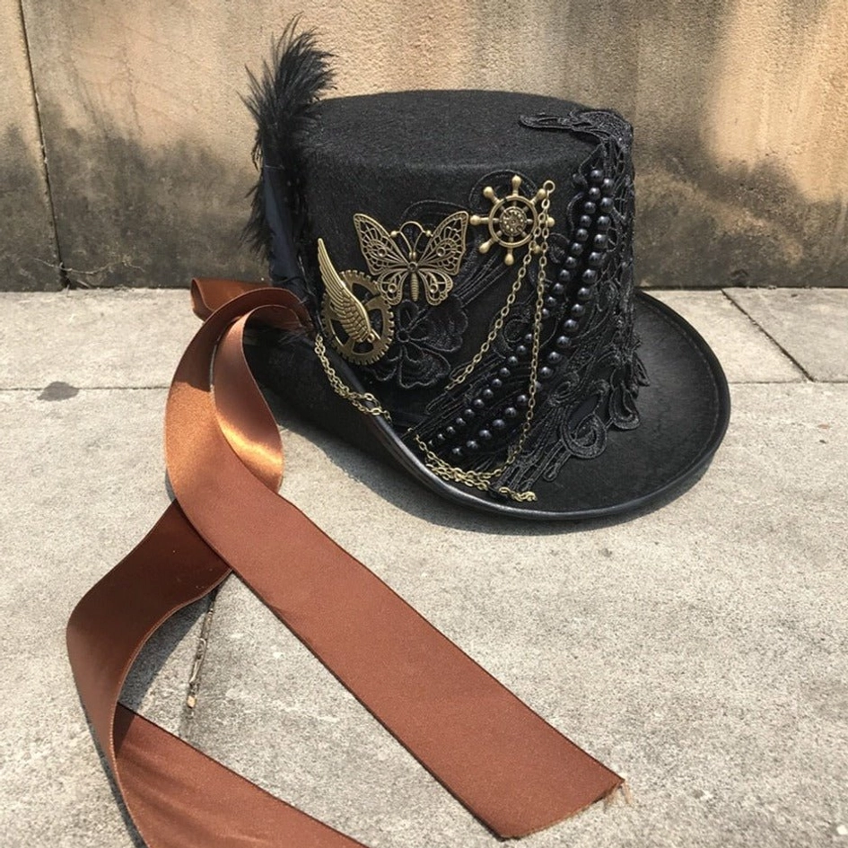 Steampunk top hat flat side view lying on concrete ground with full exterior trim display including brown satin ribbon band and bronze hardware details
