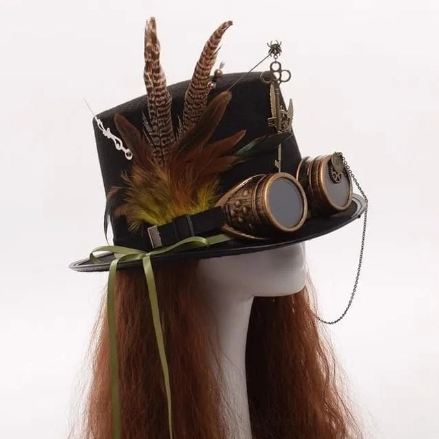 Steampunk top hat styled on mannequin with long brown wig, showing bronze goggles, pheasant feathers, green chin strap, and goggle chain attachment