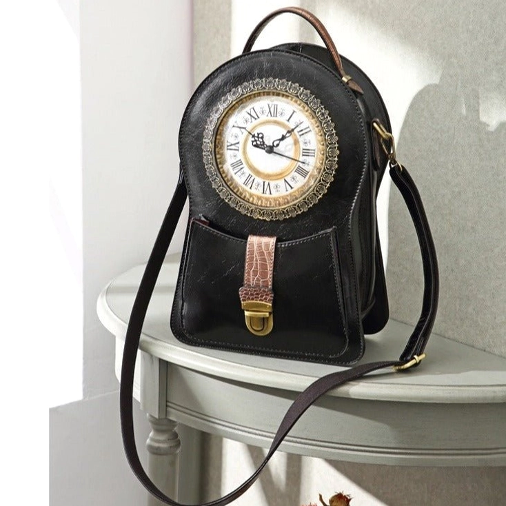 Two-tone black and brown steampunk clock crossbody bag featuring functional Roman numeral clock face, contrasting leather panels, brass hardware, and front display