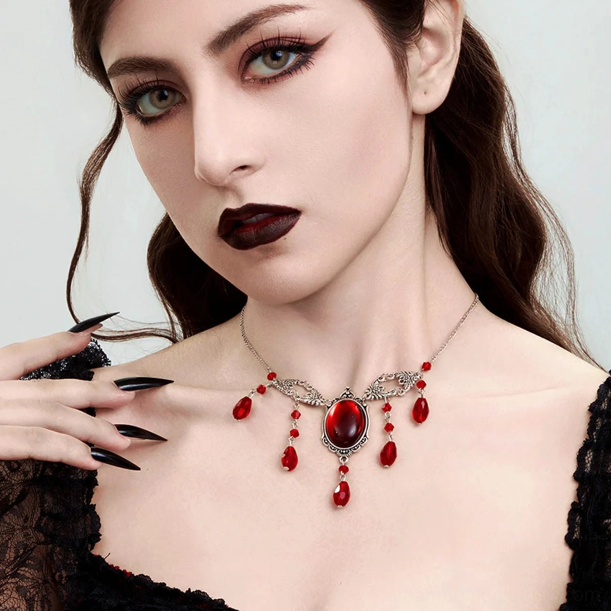Victorian steampunk vampire necklace featuring silver filigree metalwork with large red oval crystal and dangling teardrop beads, showcased on gothic model in three-quarter profile against white studio background