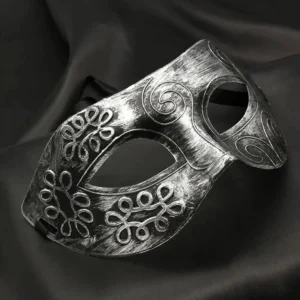 Distressed silver steampunk Venetian masquerade mask with embossed scroll and floral motifs, shown from oblique side angle on dark backdrop