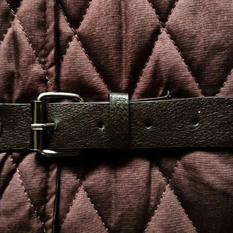 Close-up detail of brown steampunk vest leather buckle and quilted fabric texture