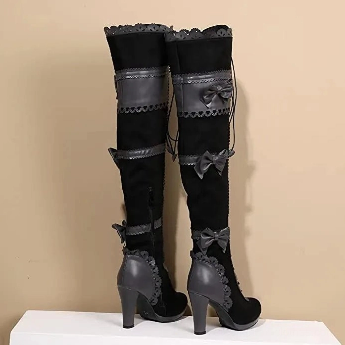 Black Victorian steampunk knee-high boots rear view displaying block heel, scalloped leather heel trim, and back bow decorations