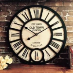 Steampunk vintage wall clock with roman numerals, 16 inch black frame, distressed off-white leather dial, front view close-up showing industrial retro design