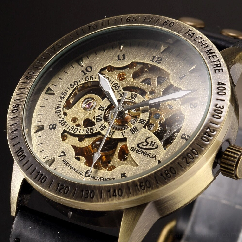Closeup of steampunk watch dial showing brushed champagne face with bronze tachymetre bezel and visible golden gear movement