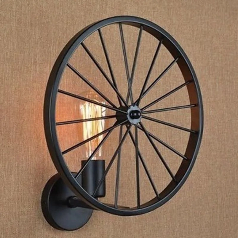 Steampunk spoked wheel wall lamp with lit Edison filament bulb, matte black metal frame mounted on white wall for home interior decor