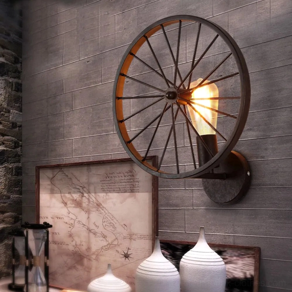Industrial steampunk wagon wheel wall lamp three-quarter view on grey accent wall with vintage tabletop ornaments, authentic vintage home decor styling