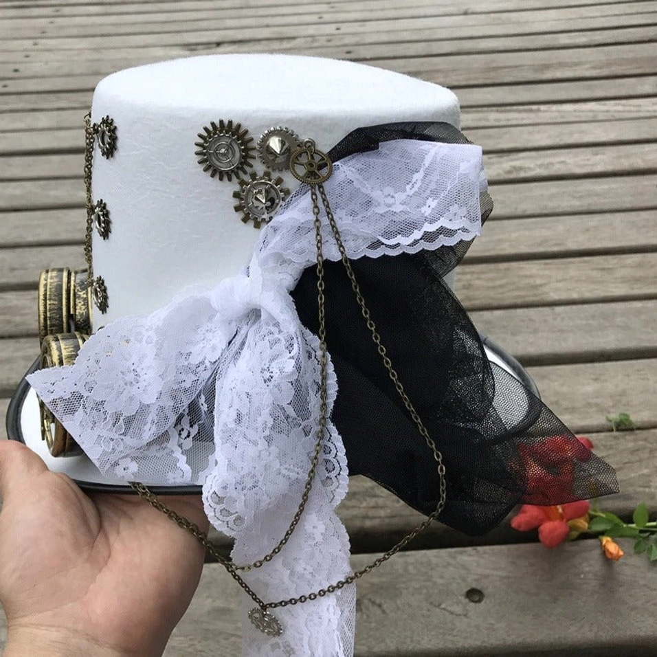 Rear view of white steampunk top hat with gear embellishments and dual-tone lace sashes, held in hand against wooden deck with red flowers