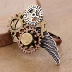 Steampunk wing gear ring with textured silver wing and multi-layer stacked gears, shown in left 3/4 view on wooden table - vintage mixed metal finish statement jewelry