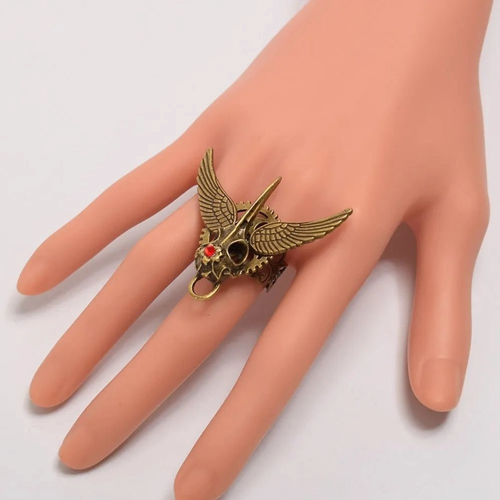 Steampunk winged skull ring worn on finger, side view showing fit and red gemstone detail on hand mannequin