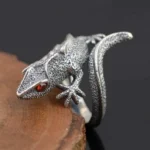 Sterling silver lizard steampunk ring left side close-up with distressed finish and red gem eye, side view on wood and dark backdrop