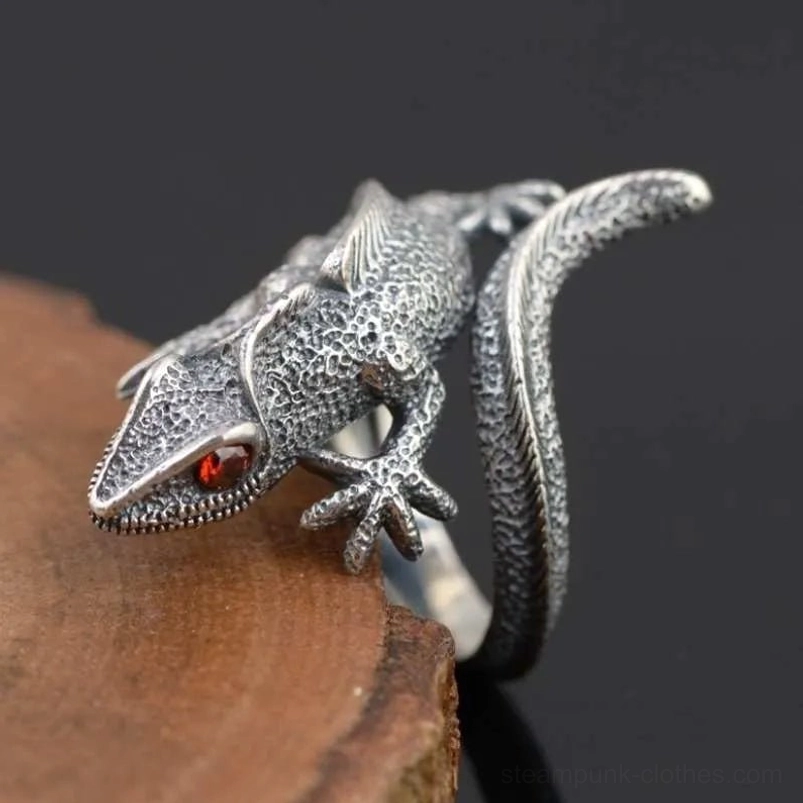 Sterling silver lizard steampunk ring left side close-up with distressed finish and red gem eye, side view on wood and dark backdrop