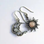 Asymmetric sun and moon steampunk earrings with antiqued silver wire wrap and natural gemstones on white background, flat lay view