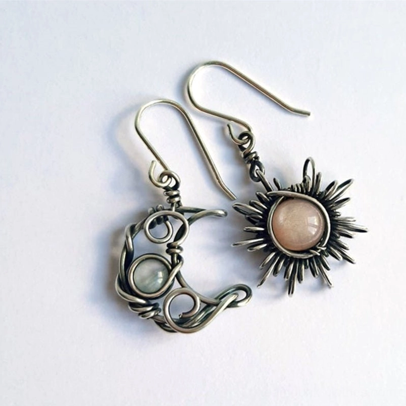 Asymmetric sun and moon steampunk earrings with antiqued silver wire wrap and natural gemstones on white background, flat lay view