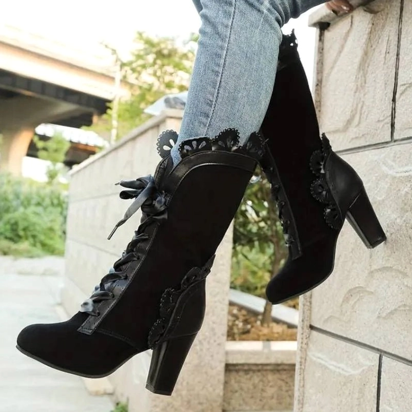 Black suede steampunk mid-calf boots with satin ribbon laces and scalloped decorative trims, Victorian-inspired design worn with light blue jeans