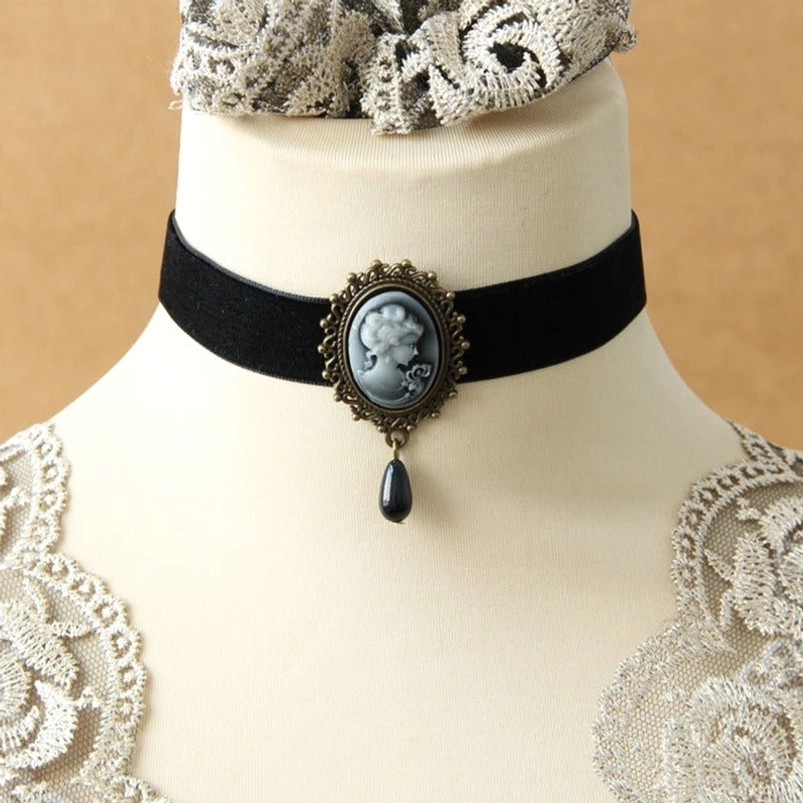 Victorian cameo choker displayed on dress form neck against lace-trimmed vintage background, highlighting ornate bronze cameo setting and teardrop pendant