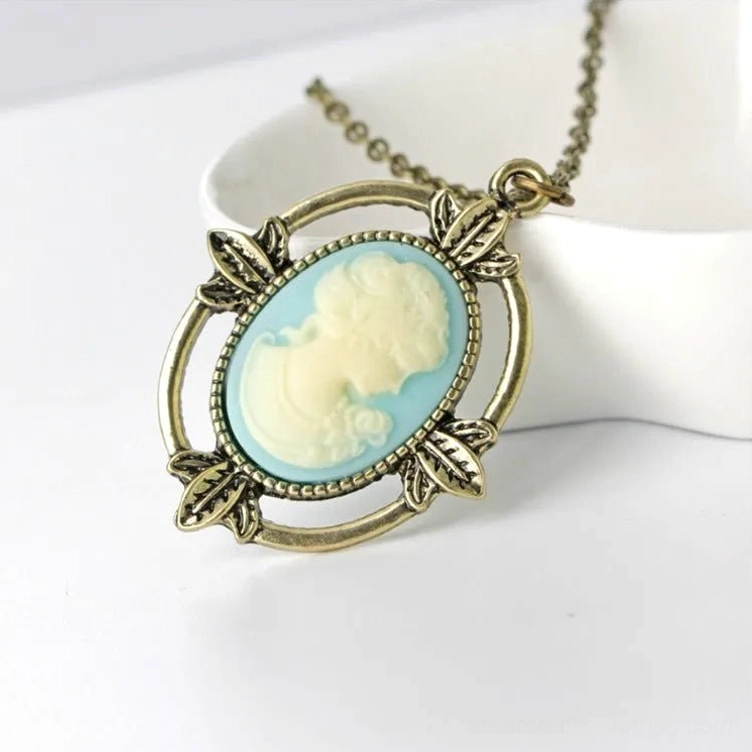 Victorian cameo profile necklace with antique bronze leaf frame on ceramic tray, steampunk jewelry style