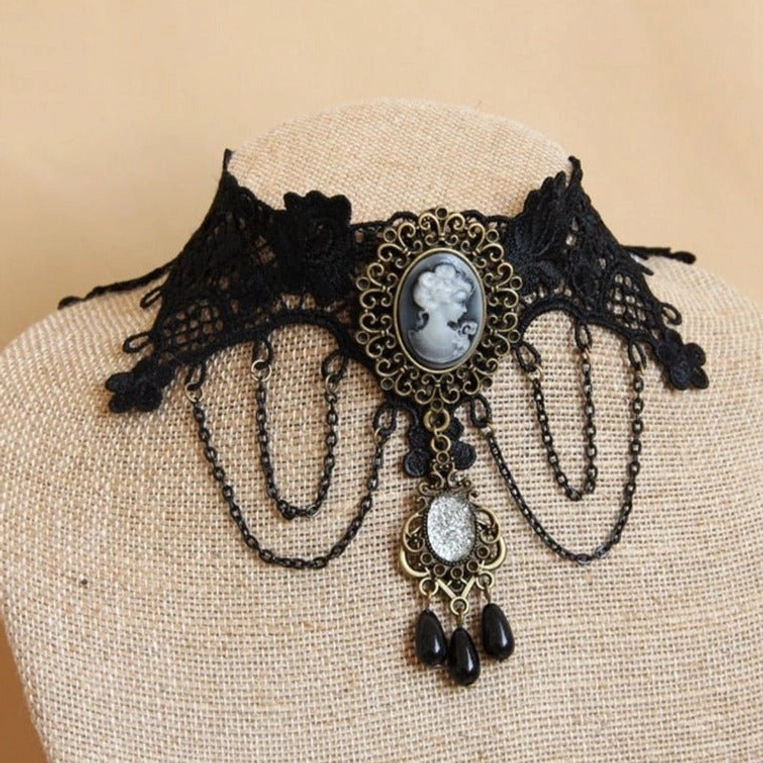 Black floral lace choker with bronze cameo ornament displayed on linen mannequin bust, featuring dangling chains and black beads - front presentation