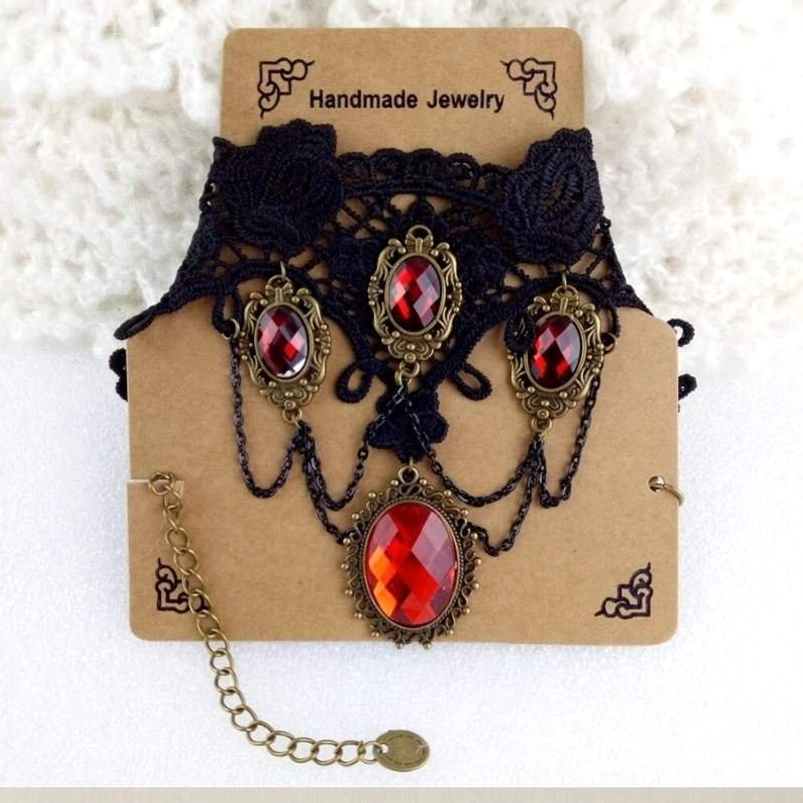Victorian vampire necklace front display - black lace choker with red gem pendant, extendable bronze metal chain, packaged on white fabric background