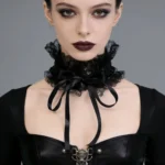 Victorian gothic lace neck collar with satin ribbon tie worn by model with dark makeup, front close-up view showing delicate black ruffled lace framing the neckline