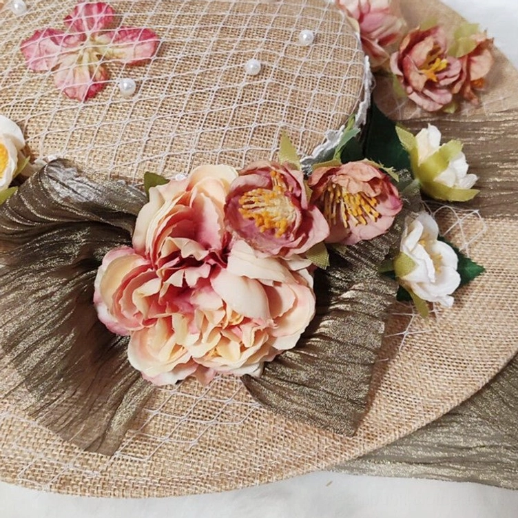 Close-up detail shot of Victorian floral hat showing pearl-decorated fishnet veil, large peony artificial flowers, and metallic pleated trim accents