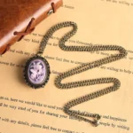 Victorian lilac cameo pocket watch necklace with twisted chain on vintage book background - steampunk jewelry flat lay