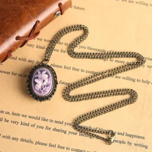 Victorian lilac cameo pocket watch necklace with twisted chain on vintage book background - steampunk jewelry flat lay