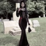 Black red Victorian strapless mermaid dress front view, worn by tattooed woman with long black hair in gothic cemetery setting, featuring lace bust trim, velvet panels, and matching long gloves