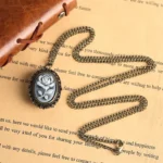 Victorian rose cameo pocket watch necklace displayed on vintage stationery background, showing bronze metal casing and resin rose cameo design - steampunk aesthetic jewelry