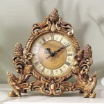 Victorian steampunk desktop clock with ornate bronze-golden carved resin frame and Roman numeral dial, front view on gray wall background