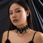 Victorian steampunk lace choker with black gem centerpiece worn on model, three-quarter view showcasing ornate floral lace pattern and layered teardrop chains against dark satin background