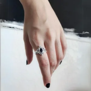Victorian steampunk onyx ring worn on hand with black nail polish, close-up side view showing marquise cut black gemstone and carved silver gothic band details