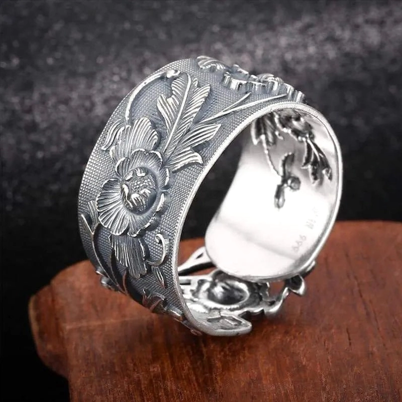 Embossed steampunk ring side view showing open adjustable band structure with carved flower and leaf motifs in antiqued silver tone