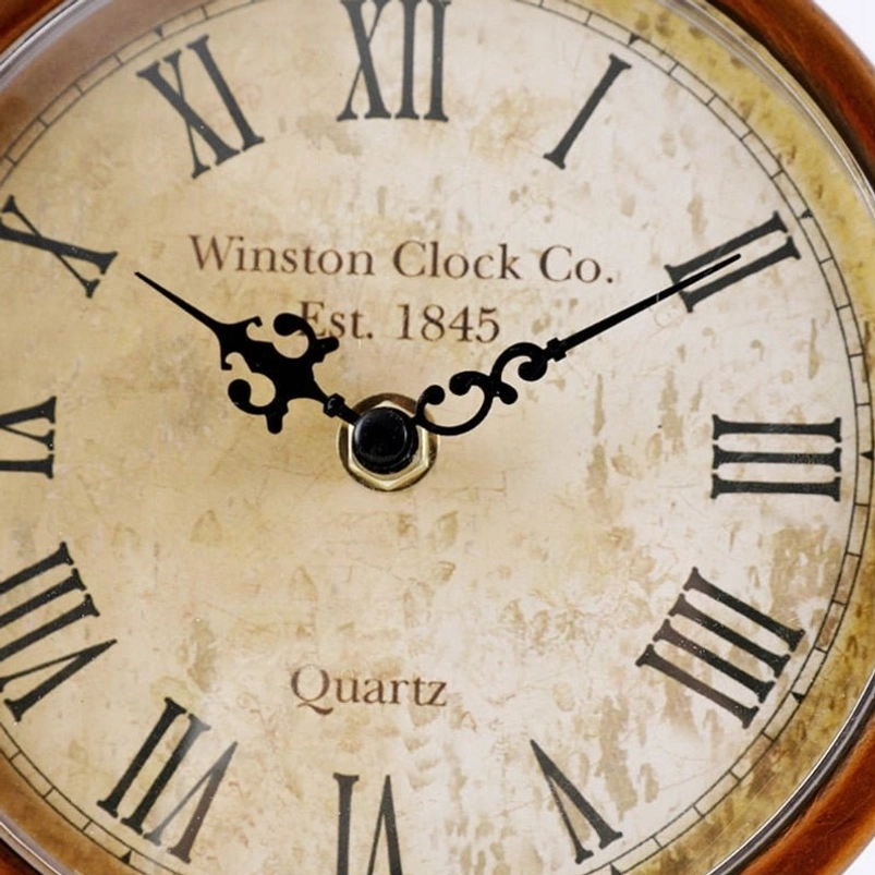 Close-up of vintage desk clock dial featuring aged paper texture, black clock hands, and Roman numerals