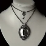 Vintage lock and key layered steampunk necklace with antique silver-tone pendant and matching mini key charm on cloth mannequin against dark studio backdrop
